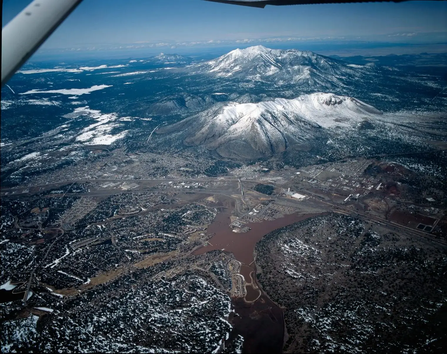 Aerial view of snow-covered mountains and a river valley.